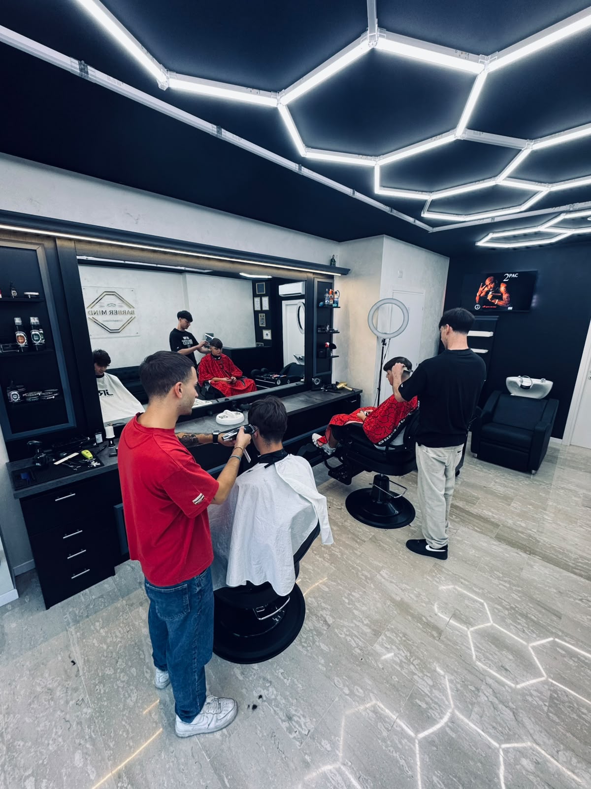 Interno di Barber Mind durante il lavoro: poltrone, specchi e luci esagonali